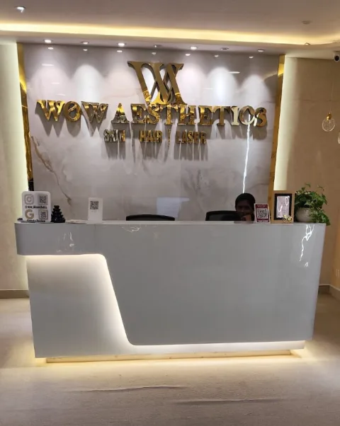Reception desk beneath the gold WOW Aesthetics logo wall at the Attapur clinic
