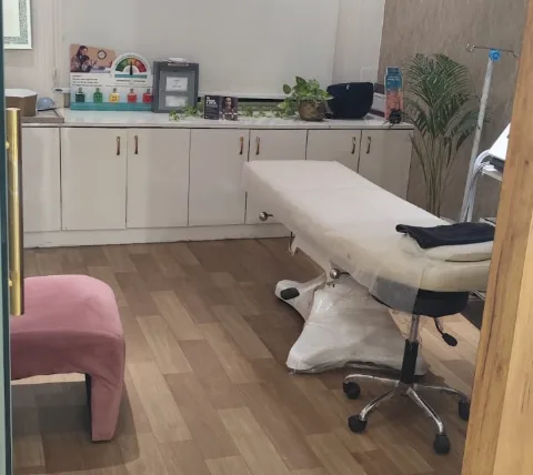 Treatment room with a covered treatment bed and white cabinets
